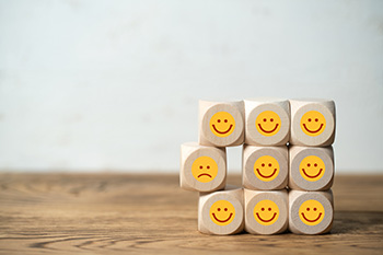 blocks with smiley faces stacked around one block with a frown
