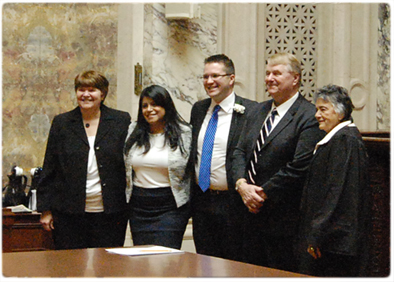 Among new members of the Legislature sworn into office by Chief Justice Shirley S. Abrahamson (right) during January was Rep. Evan Goyke, D-Milwaukee (center), son of court system Legislative Liaison Nancy Rottier (left) and husband Gary Goyke. Also pictured is Evan’s girlfriend Gabriela Leija.