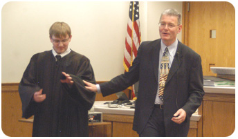 High school student Steven Schwanz of Lomira plays the role of the judge for a mock trial, as Chief Judge Storck walks the class through the court system. (Photo by Diane Graff, Watertown Daily Times) 