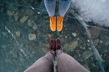birdseye view of two pairs of feet standing on crystal clear ice