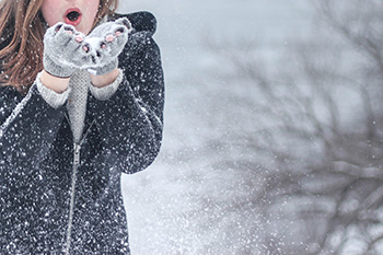 girl blowing snowflakes from her hands